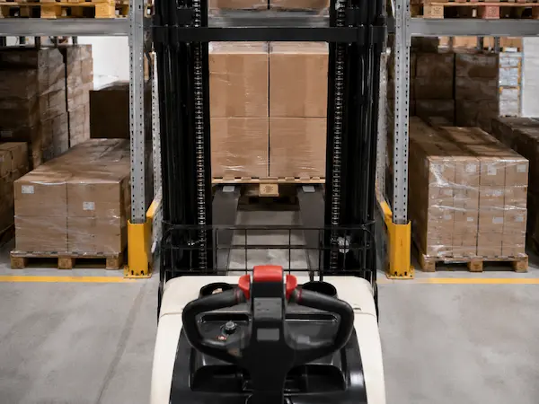 Side view of Akuros electric stacker truck with compact operator area in warehouse aisle